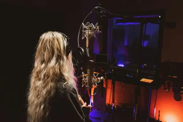 Professional voice actress in a recording studio performing multilingual dubbing and voice-over for video game character localization.